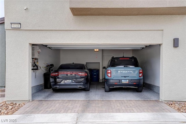garage with decorative driveway and water heater