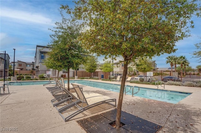 community pool with a patio, a residential view, and fence