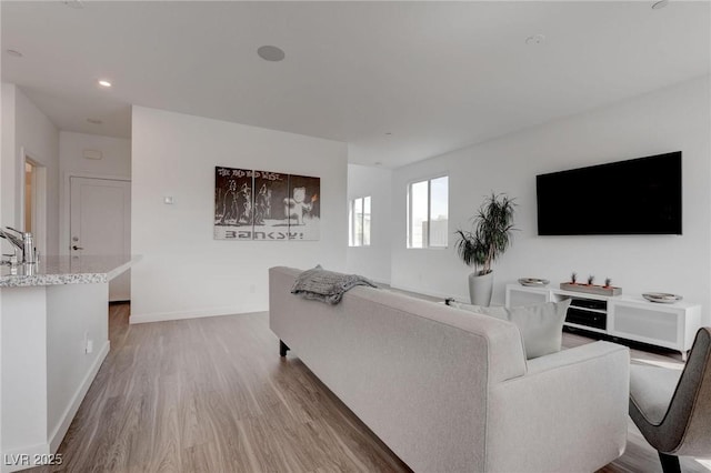 living area with light wood-type flooring, baseboards, and recessed lighting