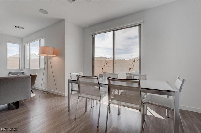 dining space with visible vents, a wealth of natural light, wood finished floors, and baseboards