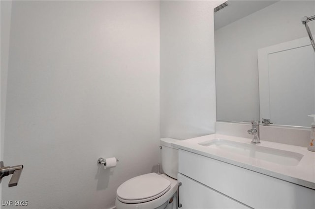 bathroom featuring toilet, vanity, and visible vents