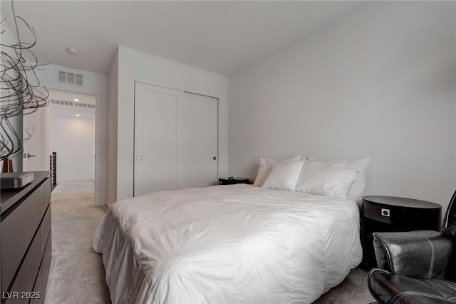 bedroom with a closet, visible vents, and light colored carpet
