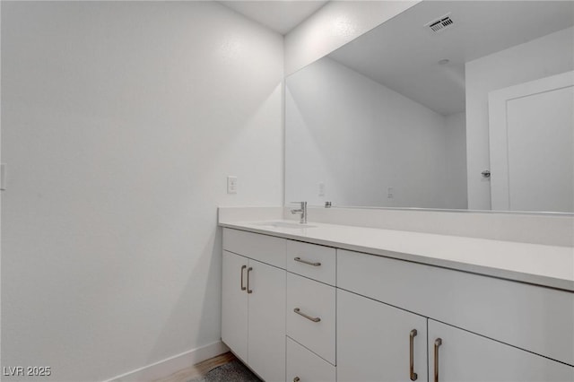 bathroom featuring wood finished floors, vanity, baseboards, and visible vents