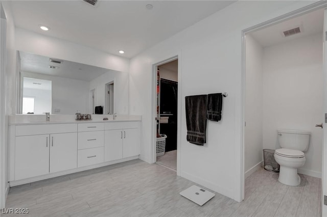 bathroom with visible vents, baseboards, a sink, and wood finished floors