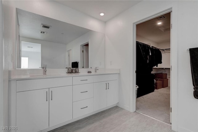 full bathroom with a sink, visible vents, a spacious closet, and double vanity