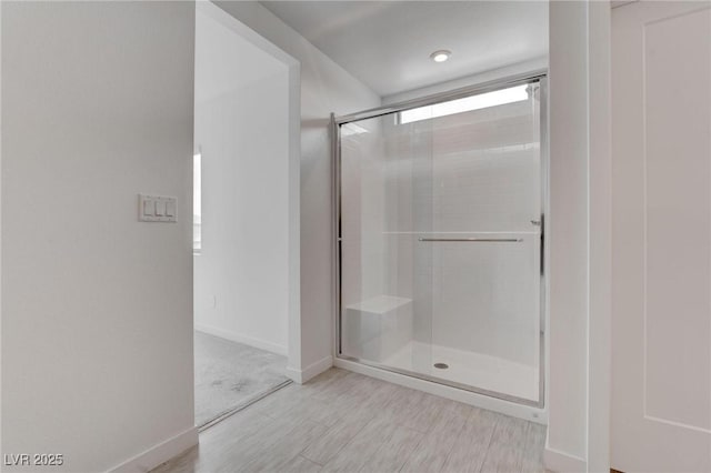 bathroom with a shower stall, baseboards, and wood finished floors