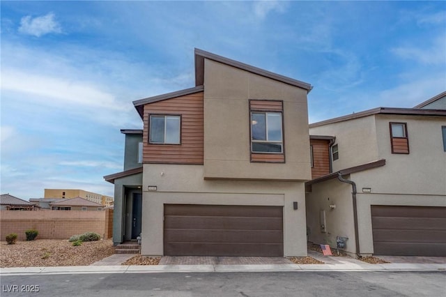 contemporary home with driveway, a garage, stucco siding, and fence