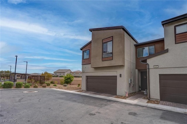 modern home with a garage, stucco siding, and fence