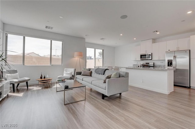 living room featuring recessed lighting, light wood-style flooring, baseboards, and visible vents