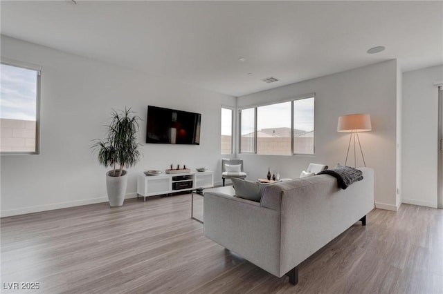 living area featuring wood finished floors, baseboards, and visible vents