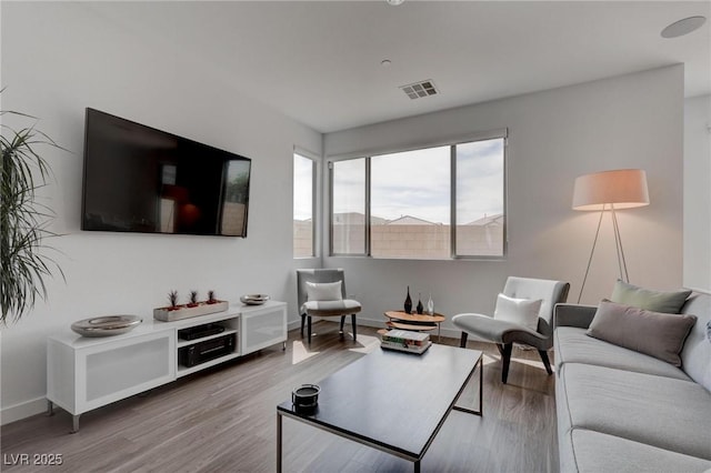 living area with visible vents, baseboards, and wood finished floors