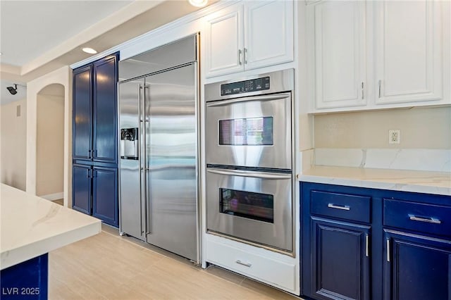 1430 October Oak Ave, Las Vegas, NV 89123 - kitchen with white cabinetry, blue cabinetry, light stone counters, and appliances with stainless steel finishes