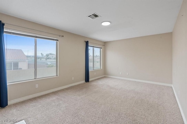 carpeted empty room with visible vents and baseboards