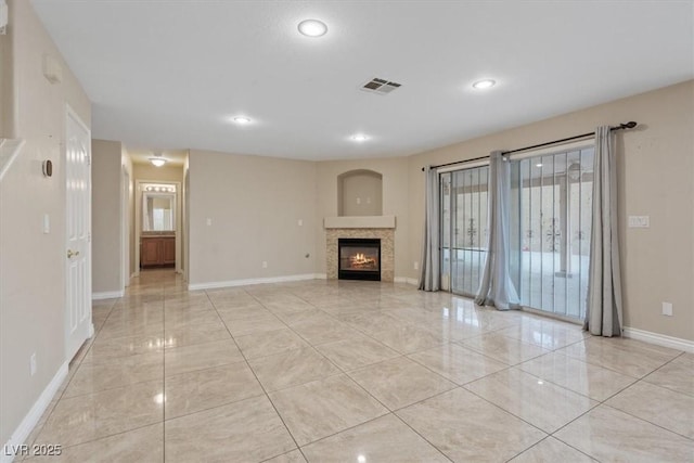 unfurnished living room featuring light tile patterned floors, baseboards, a tiled fireplace, and a healthy amount of sunlight