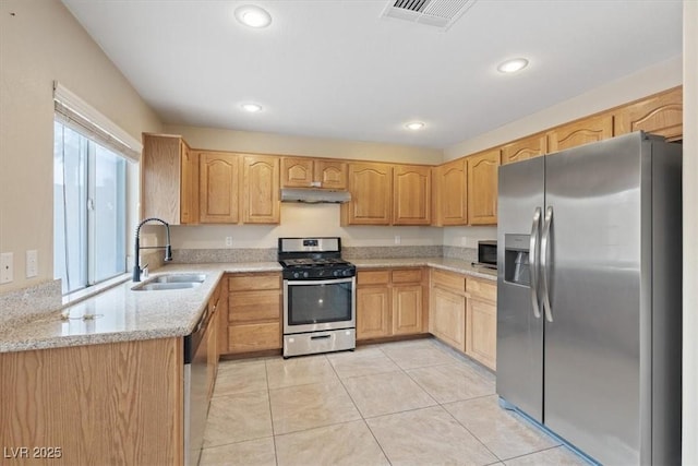 kitchen featuring a sink, under cabinet range hood, light tile patterned floors, visible vents, and appliances with stainless steel finishes