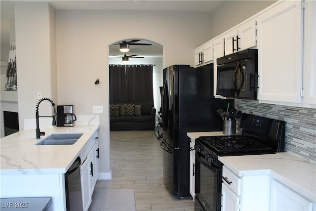 kitchen featuring a sink, a ceiling fan, black appliances, light wood finished floors, and backsplash