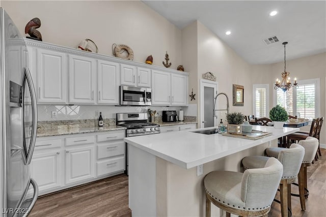 kitchen with white cabinetry, wood finished floors, stainless steel appliances, and a breakfast bar area
