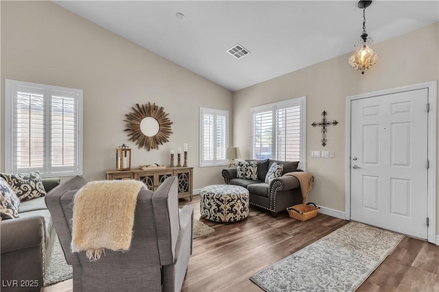 living area featuring high vaulted ceiling, baseboards, wood finished floors, and visible vents
