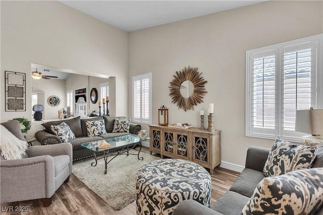 living room with baseboards, a ceiling fan, and wood finished floors