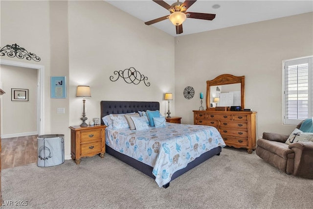 carpeted bedroom with baseboards, a ceiling fan, and high vaulted ceiling