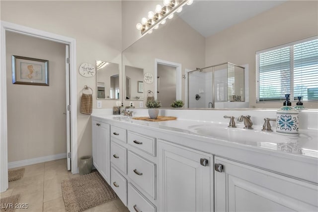 bathroom with tile patterned flooring, a sink, double vanity, and a stall shower