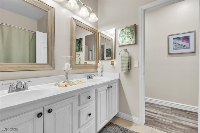 full bath with double vanity, tile patterned flooring, baseboards, and a sink