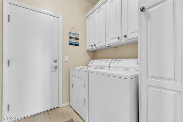laundry area featuring washing machine and clothes dryer, light tile patterned floors, and cabinet space