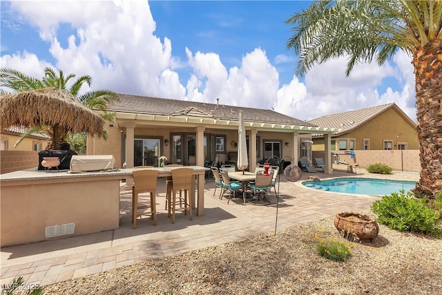 back of property featuring outdoor dry bar, fence, a patio, a fenced in pool, and stucco siding