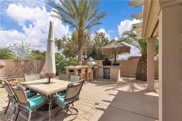 view of patio featuring a bar, area for grilling, fence, grilling area, and outdoor dining area