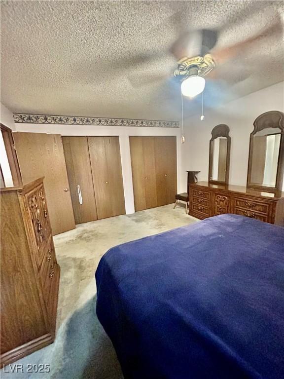 7200 Alta Dr, Las Vegas, NV 89145 - bedroom featuring two closets, a ceiling fan, a textured ceiling, and carpet
