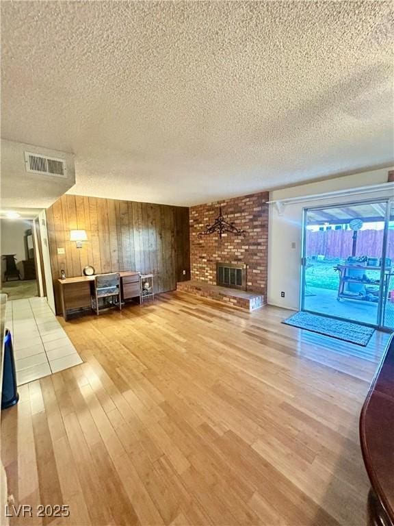 7200 Alta Dr, Las Vegas, NV 89145 - unfurnished living room with a fireplace, a textured ceiling, light wood-style flooring, and visible vents