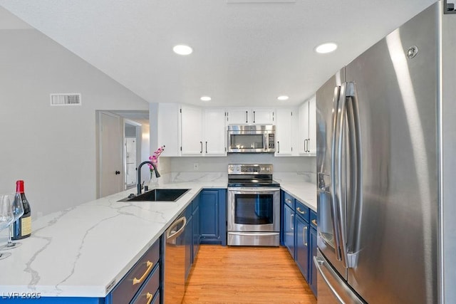 kitchen featuring a sink, light wood finished floors, blue cabinetry, appliances with stainless steel finishes, and visible vents
