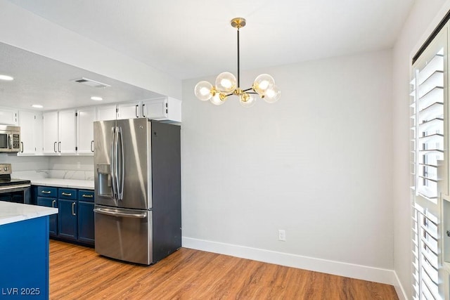 kitchen featuring blue cabinets, an inviting chandelier, stainless steel appliances, baseboards, and visible vents