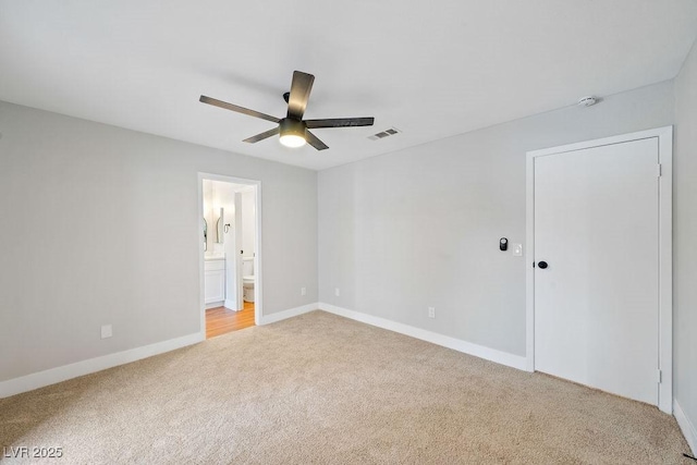 unfurnished bedroom with light carpet, ensuite bathroom, and baseboards