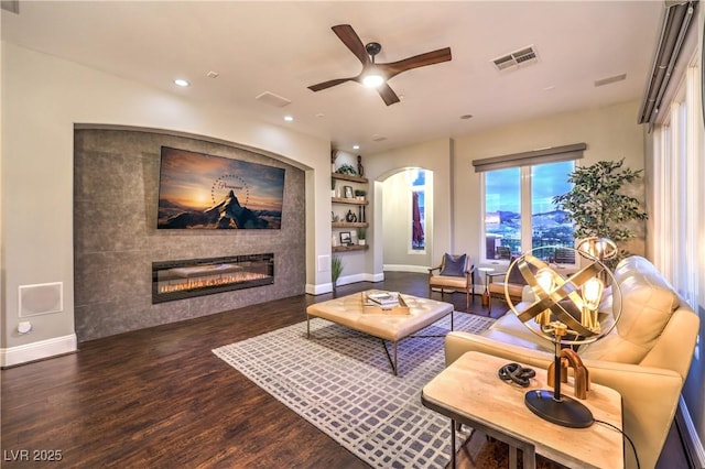 living area with wood finished floors, ceiling fan, built in shelves, and visible vents