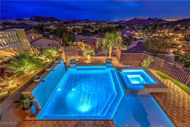 view of swimming pool with a mountain view, a fenced backyard, and a pool with connected hot tub