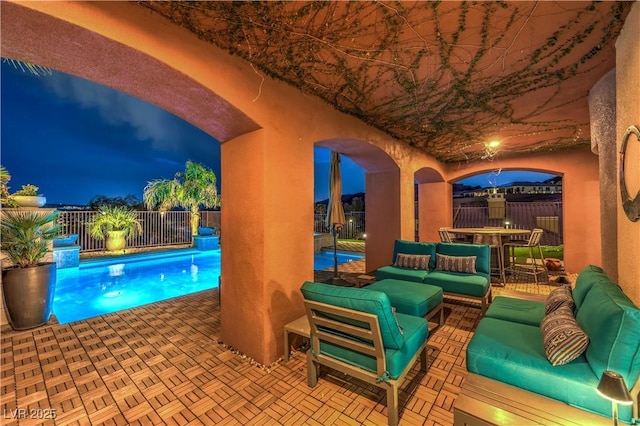 patio at night with outdoor lounge area, a fenced in pool, and fence