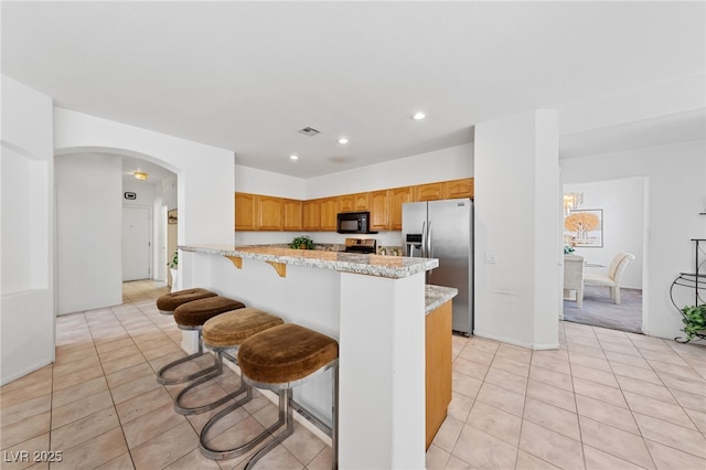 3024 Pismo Beach Dr, Las Vegas, NV 89128 - kitchen with stainless steel refrigerator with ice dispenser, black microwave, light tile patterned floors, a peninsula, and recessed lighting