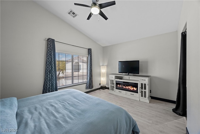 10342 Cherry Brook St, Las Vegas, NV 89183 - bedroom with lofted ceiling, visible vents, baseboards, a glass covered fireplace, and light wood-type flooring