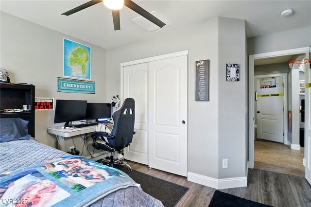 bedroom featuring wood finished floors, a closet, baseboards, an office area, and a ceiling fan