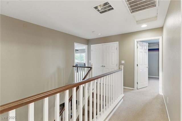 corridor featuring visible vents, baseboards, light carpet, and an upstairs landing