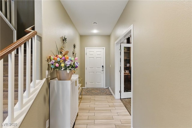 hallway with baseboards, visible vents, stairway, and wood tiled floor