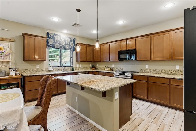 kitchen featuring visible vents, a sink, brown cabinets, and black appliances