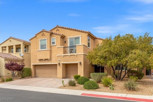 view of front of property with stucco siding, a tile roof, decorative driveway, and a garage