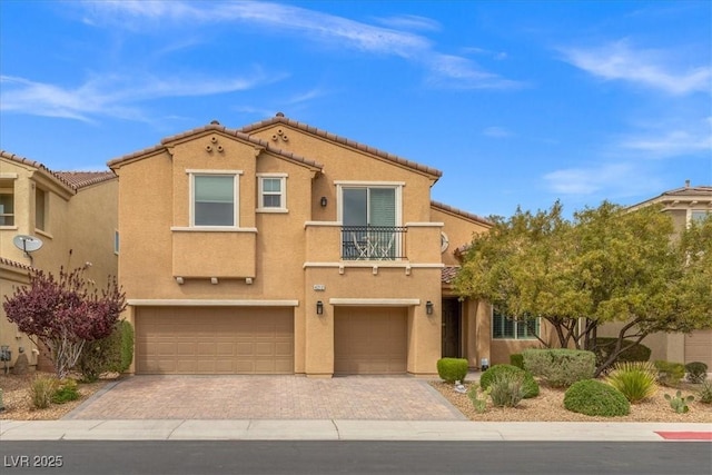 view of front facade featuring a tiled roof, stucco siding, decorative driveway, a balcony, and a garage
