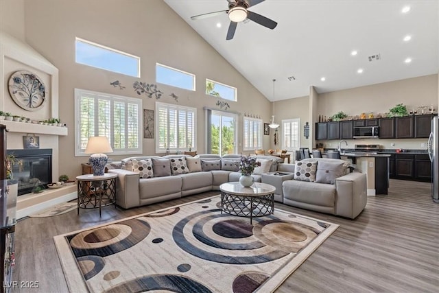 living room with light wood finished floors, plenty of natural light, high vaulted ceiling, and visible vents