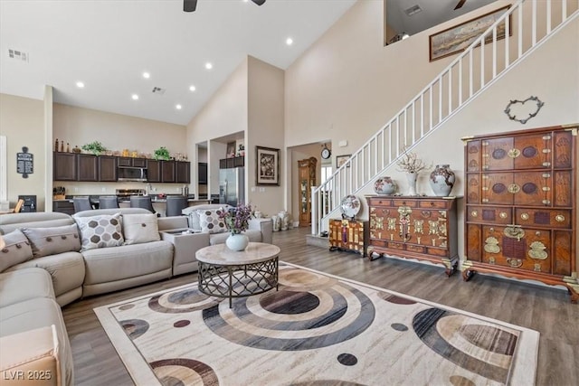 living area with visible vents, wood finished floors, stairway, and high vaulted ceiling