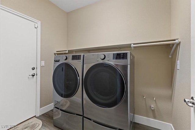 laundry area with washer and dryer, laundry area, wood finished floors, and baseboards