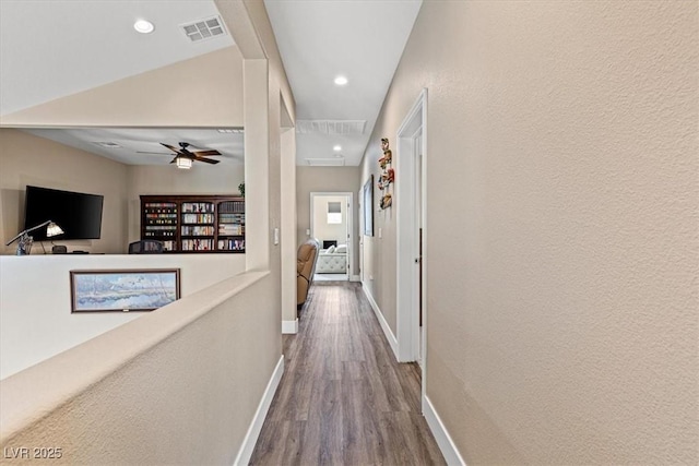 hallway with baseboards, dark wood-style flooring, visible vents, and attic access