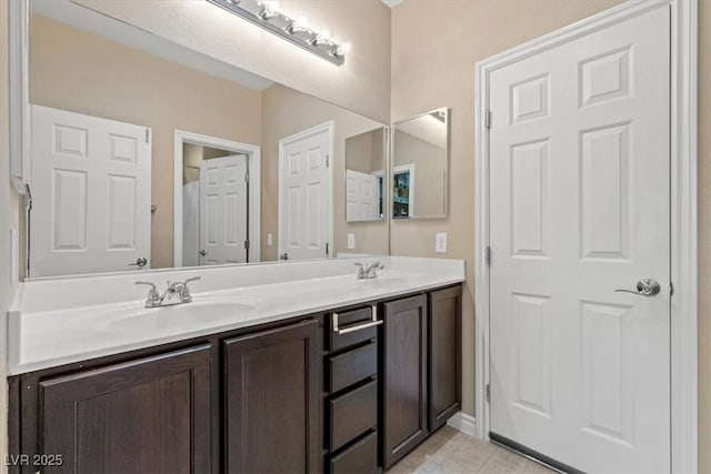 full bath with a sink, double vanity, baseboards, and tile patterned flooring